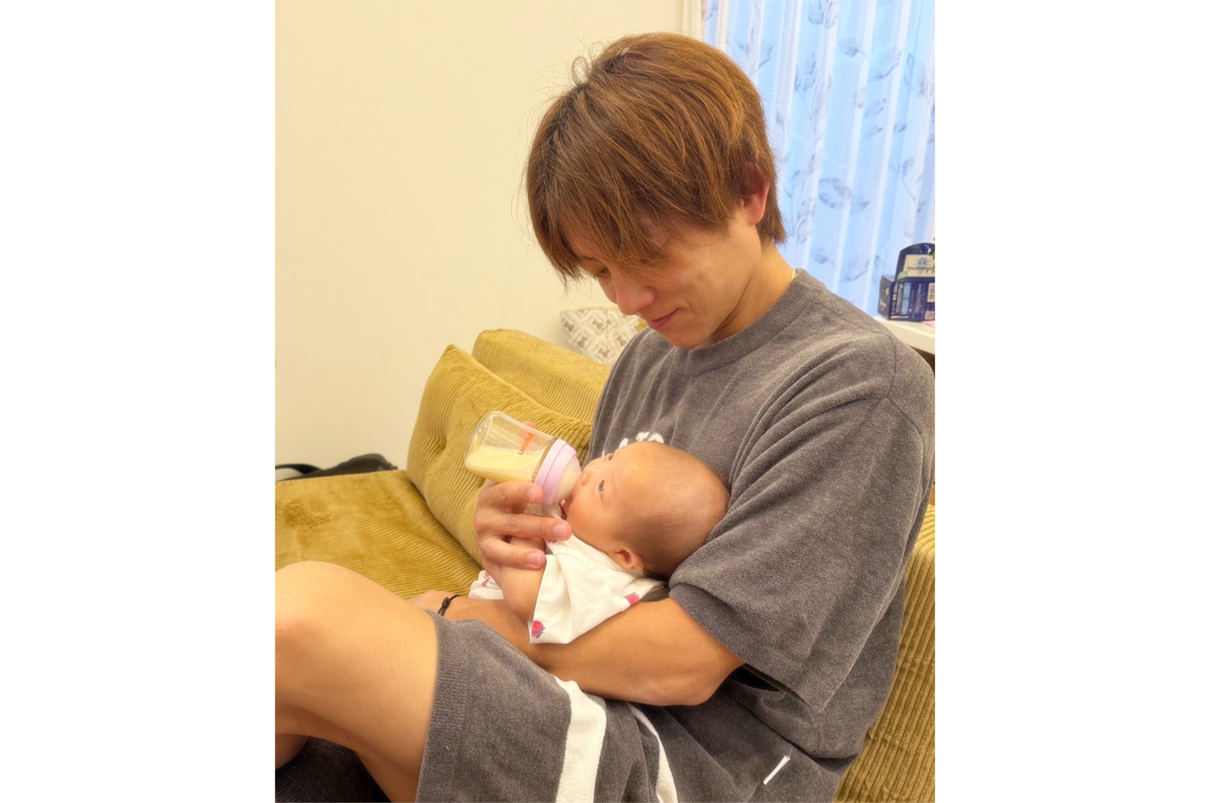 杉浦太陽さんがお子さんに哺乳瓶でミルクを与えている画像